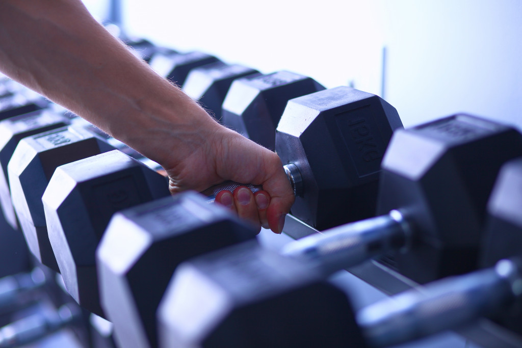 a hand of a person lifting dumbbells from a rack