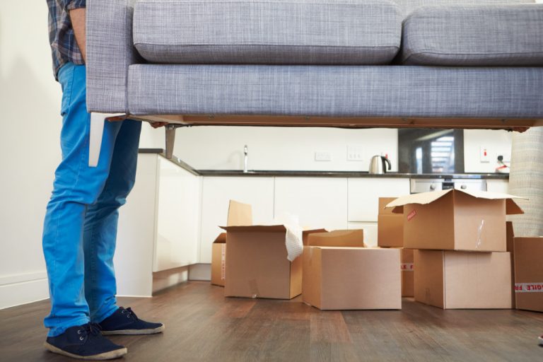Man shifting sofa and boxes in the background