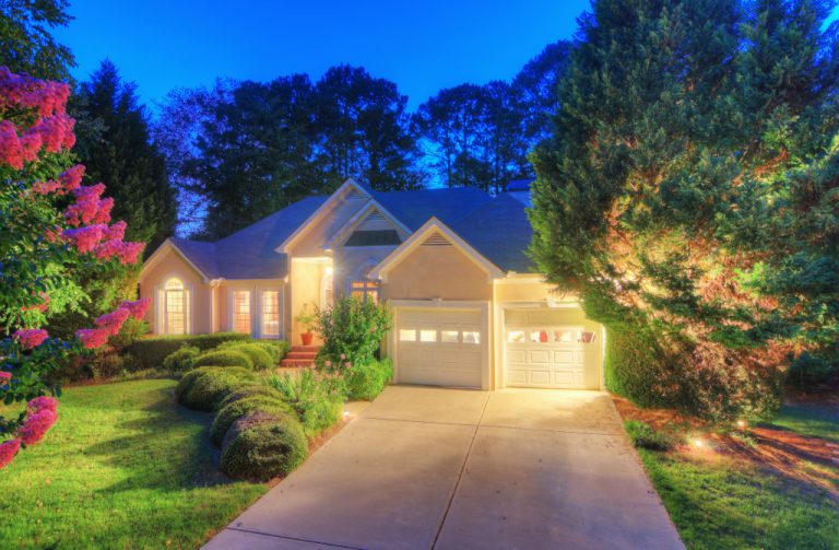 A well-lit home's neat and well-maintained facade pictured at dusk